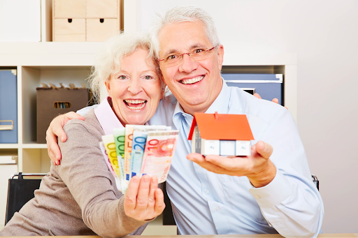 Elderly couple with money and house model